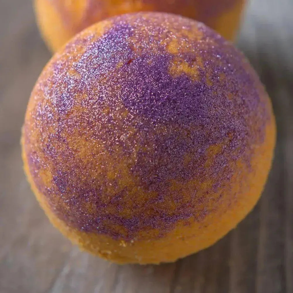Vibrant bath bomb with shimmering purple and orange glitter, perfect for creating colorful and eco-friendly bath experiences.
