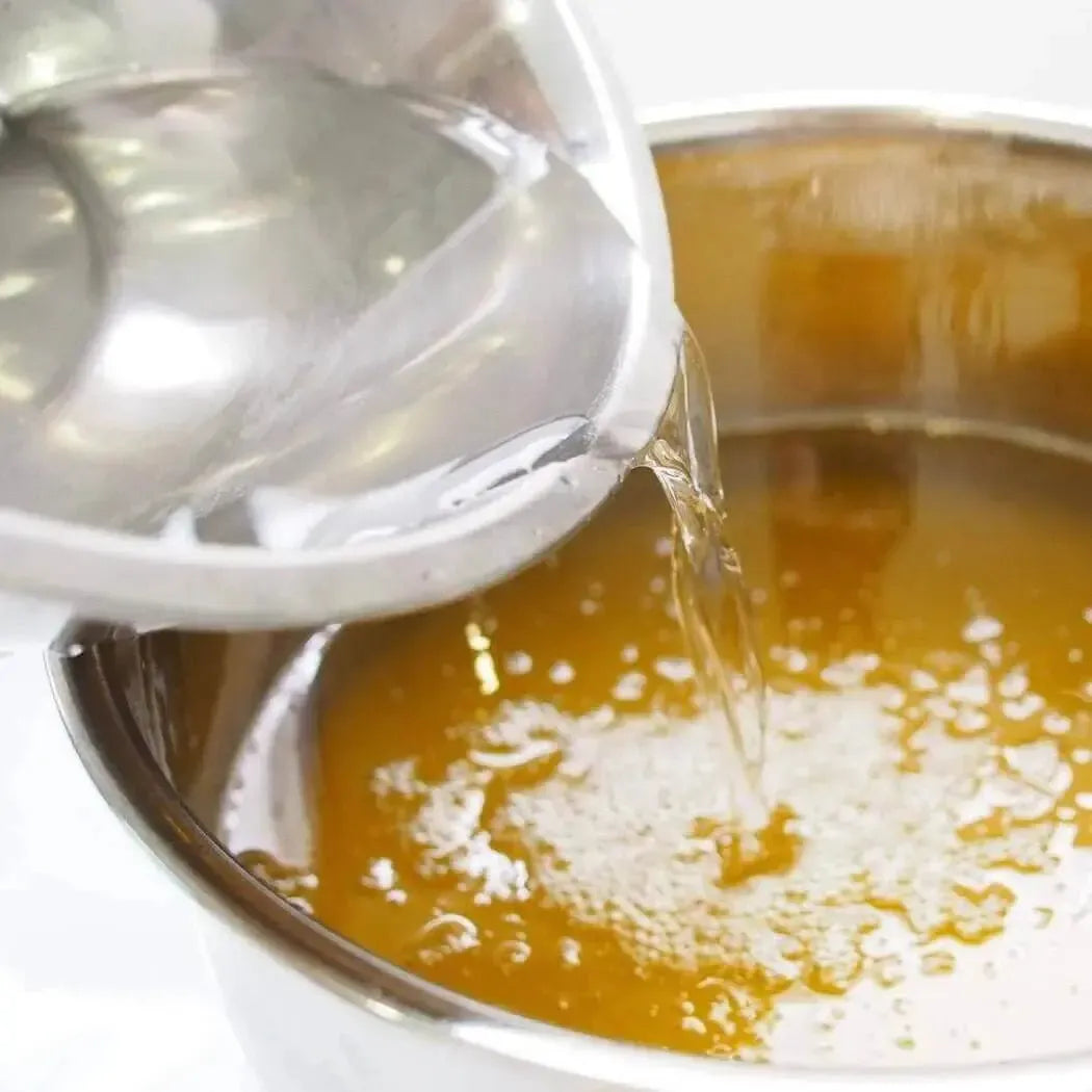 Pouring liquid into a pot, creating bubbles in a warm golden broth.