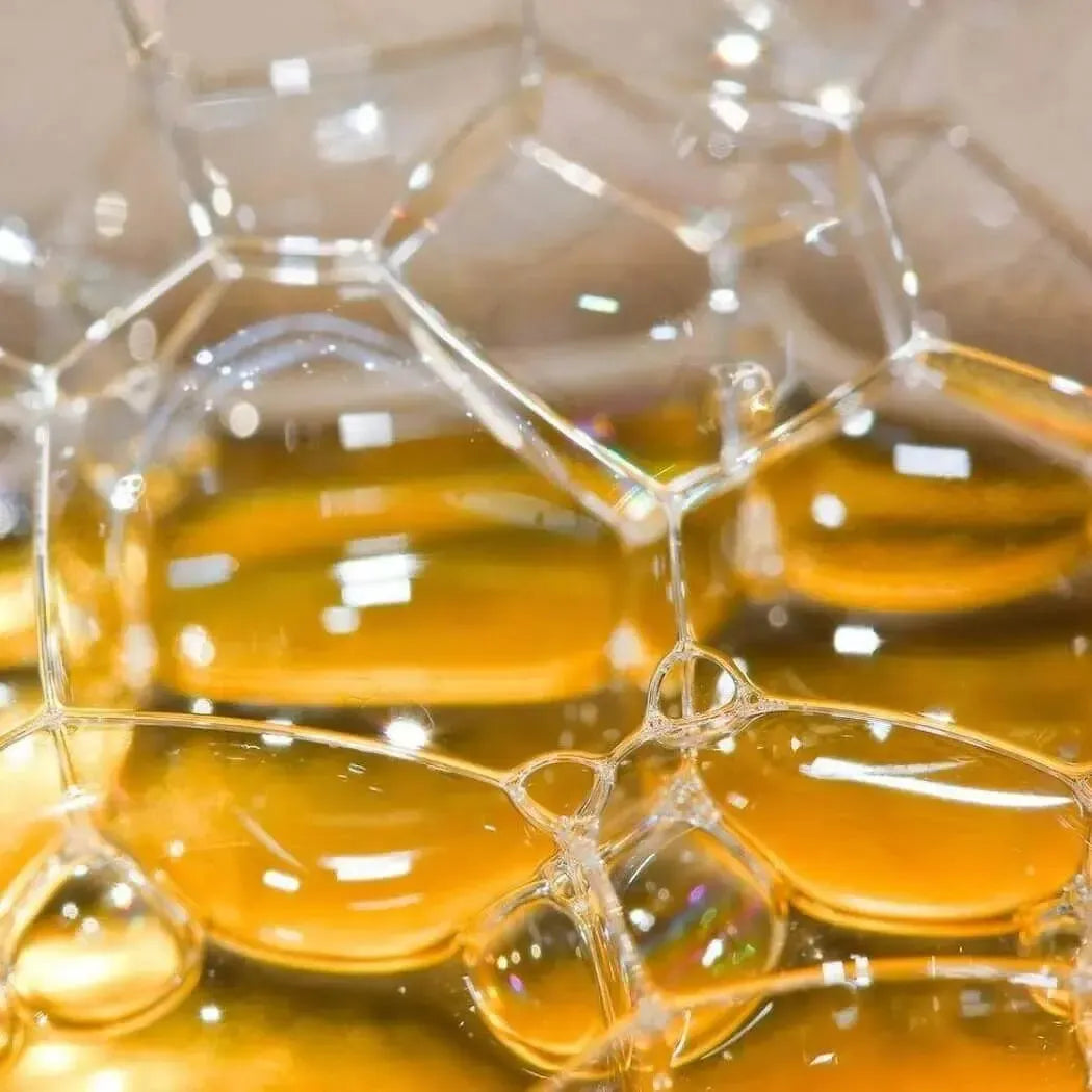 Close-up of bubbles highlighting the golden hue of sodium lactate in skincare products.