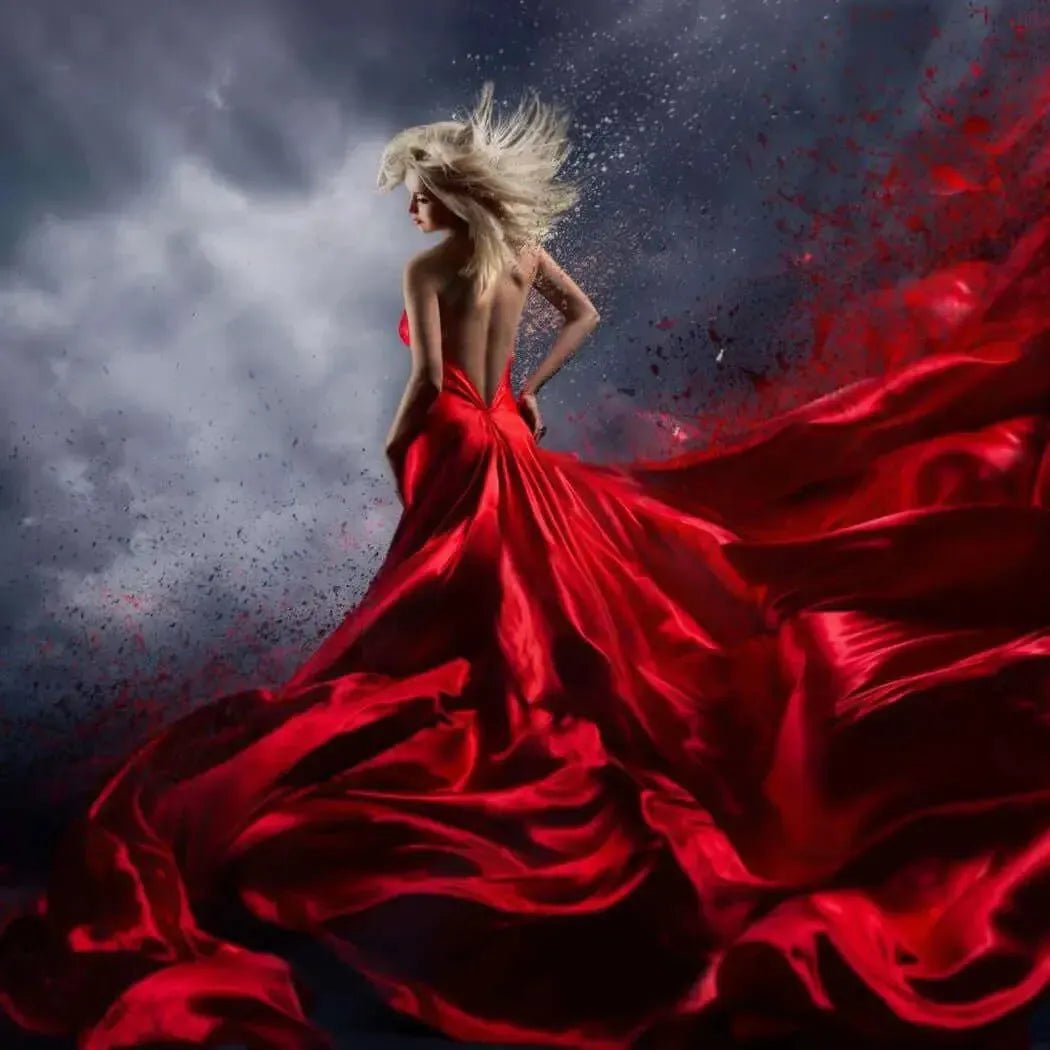 Elegant woman in a flowing red gown against a dramatic stormy background.