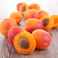 Fresh, juicy apricots sliced in half, showcasing their sweet, vibrant flesh and pit on a rustic wooden background.