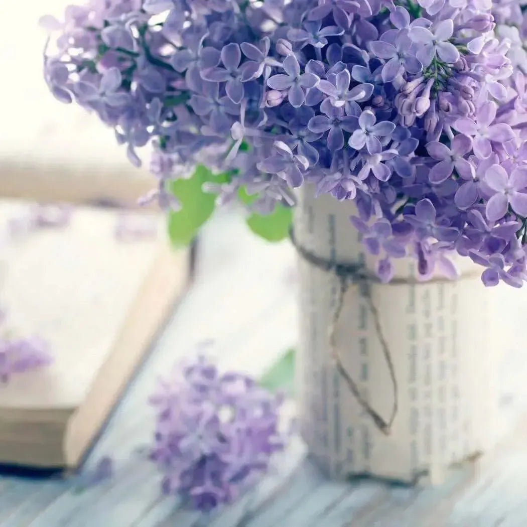 Beautiful lilac blossoms in a rustic jar with an open book, evoking springtime freshness and floral elegance.