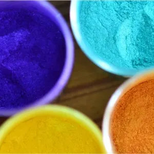 Vibrant colored powders in cups: purple, blue, orange, and yellow, perfect for art and decoration projects.