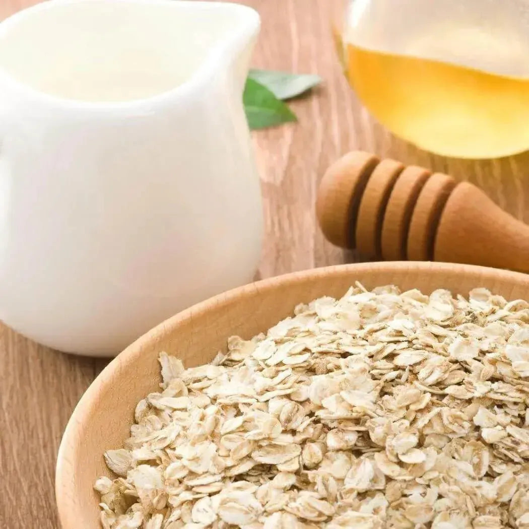 Bowl of oats with milk, honey, and a wooden honey dipper for a soothing fragrance oil experience.