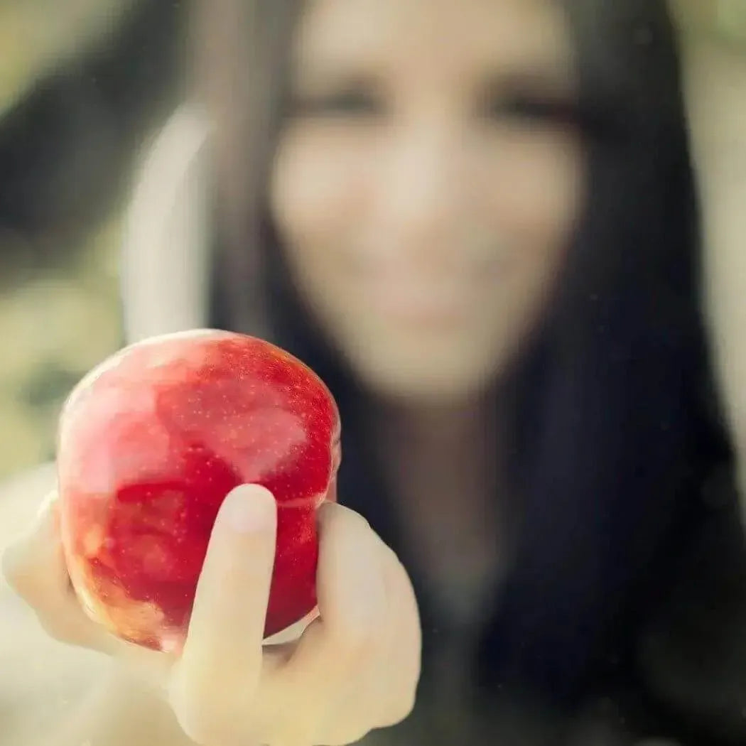 A mysterious woman holding a shiny red apple, evoking magic and fairytale themes.
