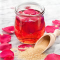 Glass jar of rose petal preserves with sugar and rose petals, showcasing sweet floral aroma and vibrant colors.